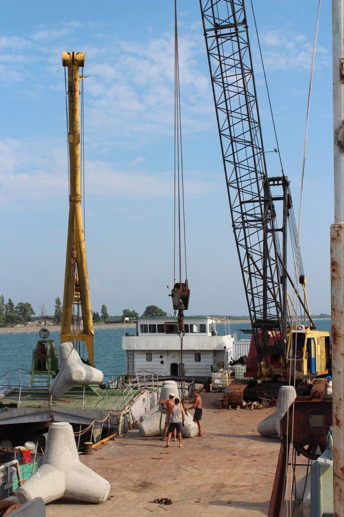 Two cranes working from a barge, lowering concrete tetrapods